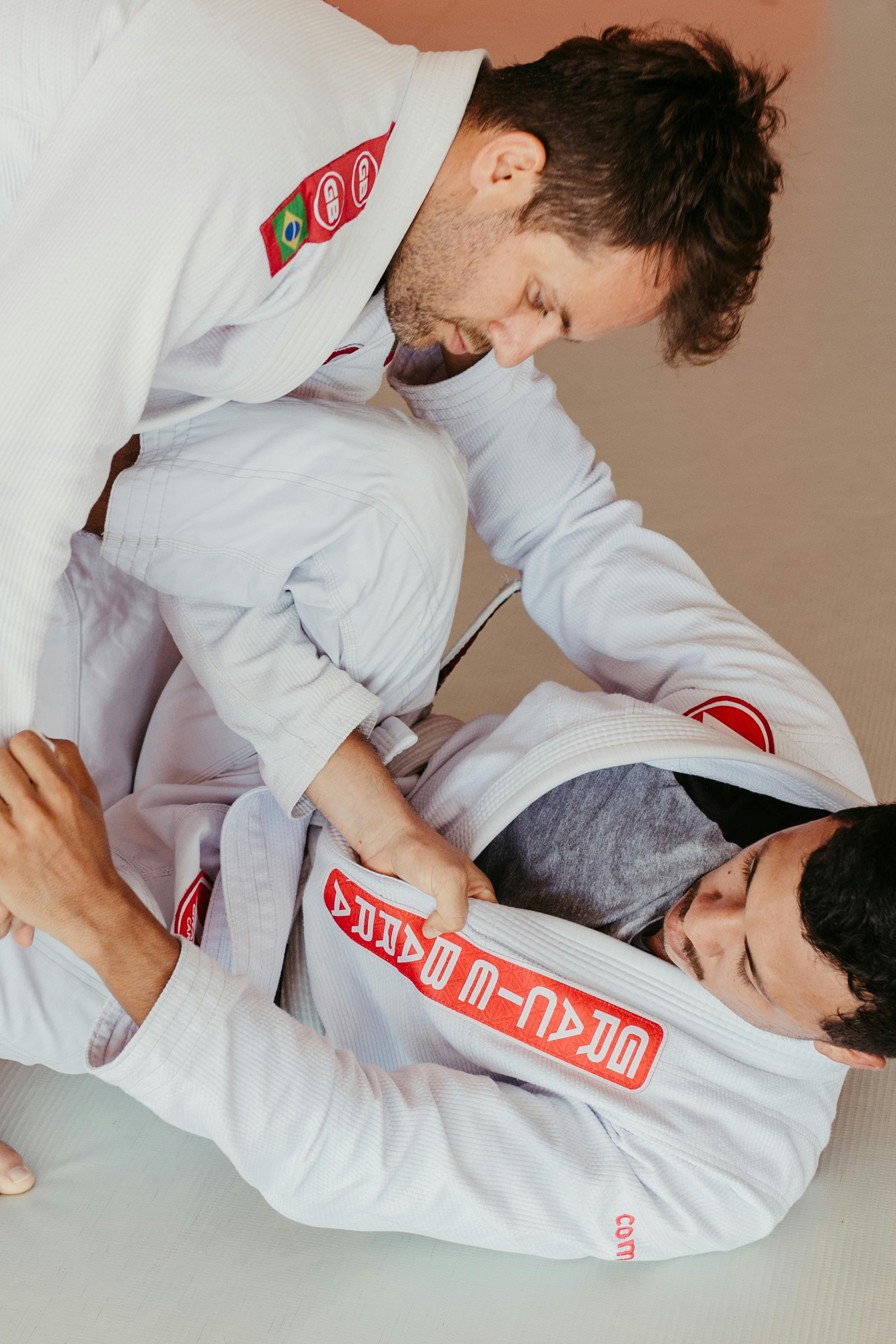 Row of colored BJJ belts ranging from white to black hanging neatly against a dark textured wall